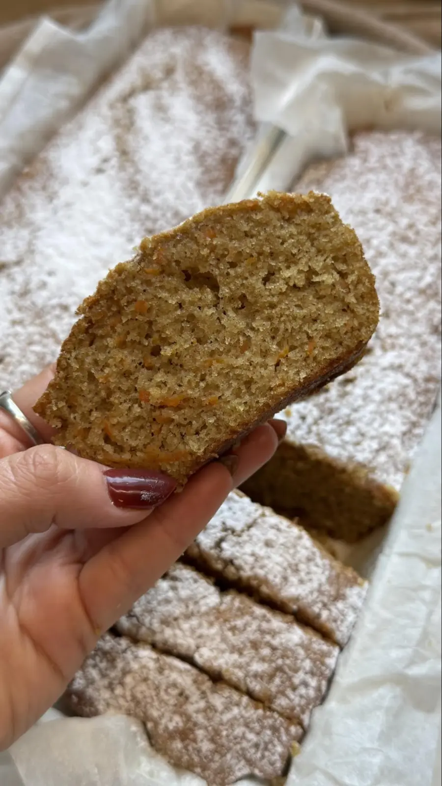 יד מרימה פרוסת עוגה מעל התבנית המאובקת בסוכר